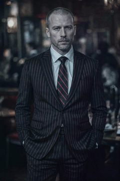 AI generated video: Close-up portrait photograph of a man, pin striped black tuxedo with red…