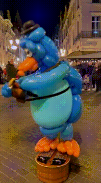 AI generated video: A blue balloon penguin performing music on a city square, street lights and…