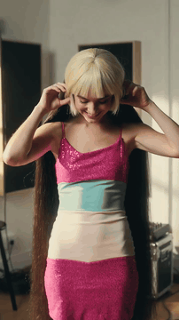 AI generated video: A joyful popstar woman in pop dress with blonde bob wig hiding up all of her…