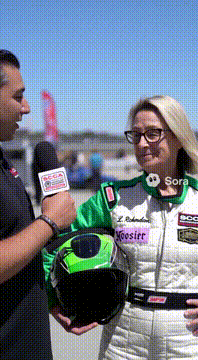 AI generated video: @laineyr Wearing a race car driver outfit, being interviewed for the SCCA…