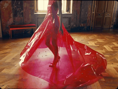 AI generated video: A woman wearing a red plastic ball gown is twirling in a palace hall. There are…