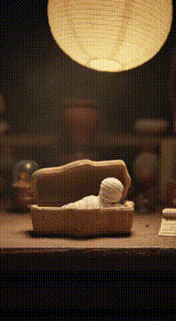 AI generated video: Duration: 10 seconds. Stop-motion look. A tiny, cute linen-wrapped “mummy-like”…