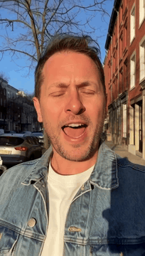 AI generated video: Natural eye-level vlog shot of a man wearing a denim jacket walking down a…