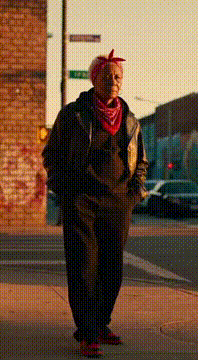 AI generated video: Blood grandma wearing gang attire with a red bandanna tied around her head and…
