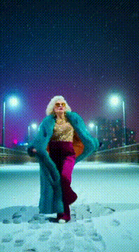 AI generated video: SCENE: 冬の夜、粉雪が舞う静かな都会の橋。路面は薄く雪が積もり、街灯と高層ビルの光が反射して輝いている。ファンキーばあちゃんサングラス金髪派手衣装が橋の中…