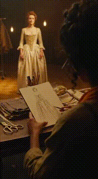 AI generated video: Cinematic fashion film set, costume designer sketching while actress in…