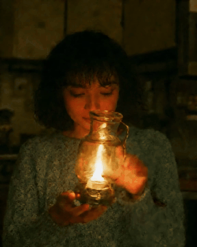 Видео, сгенерированное нейросетью: Close-up of a young woman in a worn blue sweater sitting in a dim kitchen…
